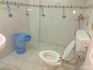 a bathroom with a toilet and a blue trash can at Hotel Basera in Dalhousie
