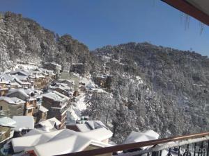 a group of buildings on a mountain with snow on it at Hotel Basera in Dalhousie