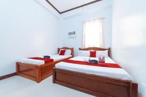 two beds in a room with white walls and a window at RedDoorz @ D Maagma Street in Kalibo