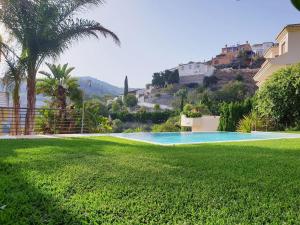 una piscina en un patio con palmeras y casas en Bonita casa en Cotobro en Almuñécar