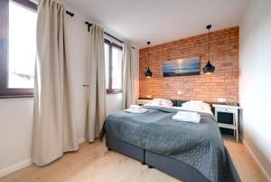 sypialnia z łóżkiem i ceglaną ścianą w obiekcie Apartamenty Bema4 Sopot w mieście Sopot