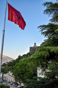 a red flag on a pole with a castle on a hill at Hotel Sofra in Gjirokastër