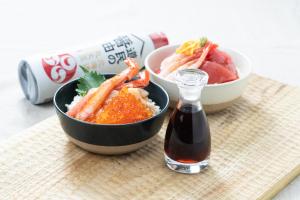 a bowl of shrimp and a bowl of rice with a bottle of sauce at Vessel Hotel Campana Susukino in Sapporo