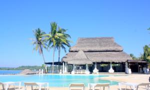 a pool at a resort with chairs and palm trees at Playa Tropical Resort Hotel in Currimao