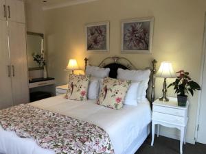 1 dormitorio con 1 cama blanca con almohadas y 2 lámparas en Cherry Berry Guest House, en George
