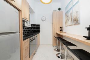 uma cozinha com paredes brancas, armários de madeira e electrodomésticos pretos em Lyto by Heloni Apartments em Atenas