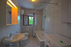 a bathroom with a sink and a toilet and a bath tub at Villa Gloria by PosarelliVillas in Lucignano +17 photos