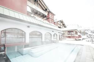 un bâtiment avec une piscine dans la neige dans l'établissement Hotel Rigele Royal Superior, à Obertauern