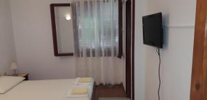 a bedroom with a bed and a tv and a window at Apartment Perović in Baška Voda