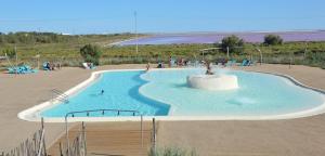 a large swimming pool with people sitting around it at Camping Les Bois Flottés in Salin-de-Giraud