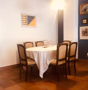 a dining room table with a white tablecloth and chairs at Casa da Aldeia - Guest House in Odiáxere