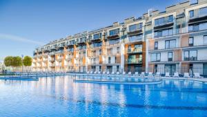 a large apartment building next to a body of water at Apartament Siesta Sunny Spa in Kołobrzeg
