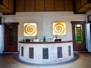 two people sitting at a reception desk in a building at Playa Tropical Resort Hotel in Currimao