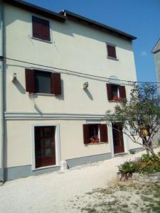 a white building with brown windows and a tree at Mon Perin Castrum - Studio Apartment Castel in Bale