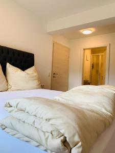 Hideaway Obertraun في اوبرترون: غرفة نوم مع سرير أبيض كبير مع اللوح الأمامي الأسود
