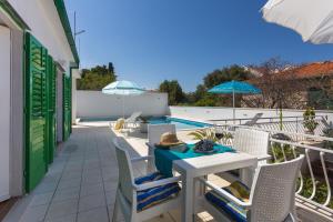 een patio met een tafel, stoelen en parasols bij Aras Wind Rose in Supetar