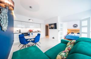 a living room with a green couch and blue chairs at Black & White Apartments in Koszalin