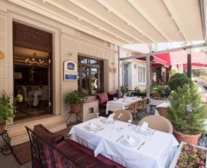 イスタンブールにあるGLK PREMIER Regency Suites & Spaの白いテーブルと椅子が備わるレストラン