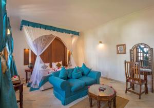a living room with a blue couch and a bed at The Seyyida Hotel and Spa in Zanzibar City