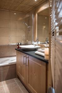 a bathroom with a sink and a bath tub at CGH Résidence Boutique Le Lodge des Neiges in Tignes