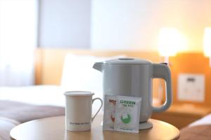 una cafetera y una taza sobre una mesa en Hotel Hokke Club Oita en Oita