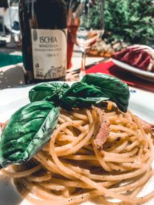 een bord pasta met basilicum en vlees en een fles wijn bij Hotel Terme Zi Carmela in Ischia