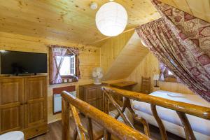 Dormitorio con cabaña de madera, cama y TV en Ubytovanie Koliba Pacho - Zrub Evka, en Prievidza