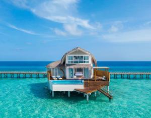 ein Haus am Wasser neben einem Pier in der Unterkunft JW Marriott Maldives Resort & Spa in Funadhoo