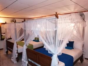 2 camas en una habitación con cortinas blancas en Suriya Homestay Mirissa en Mirissa