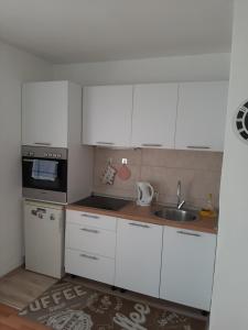 una pequeña cocina con armarios blancos y fregadero en Apartman Vills, en Sarajevo