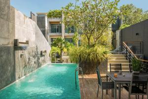 uma piscina com mesa e cadeiras ao lado de um edifício em Luxurious SeaView 4br Private Pool Villa by Intira Villas em Praia de Rawai