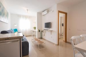 cocina y sala de estar con sofá y TV en LU&CIA City Beach Puerto 2 en Málaga
