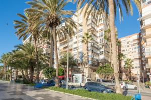 un edificio alto con palmeras delante en LU&CIA City Beach Malagueta 2, en Málaga