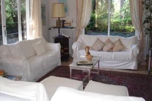 una sala de estar con muebles blancos y ventanas grandes. en Villa Eden, en Menton
