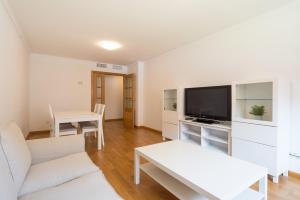 een woonkamer met een witte bank en een tv bij LU&CIA City Centre LAS AMERICAS in Málaga