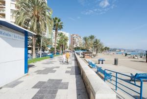 dwoje ludzi spacerujących po chodniku obok plaży w obiekcie LU&CIA City Beach Malagueta 6 w Maladze