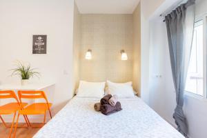 misia leżącego na łóżku w pokoju w obiekcie LU&CIA City Beach Malagueta 6 w Maladze