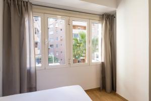 a bedroom with two windows and a bed in front thereof at LU&CIA City Beach Malagueta 2 in M&aacute;laga