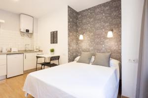 1 dormitorio con 1 cama blanca y cocina en LU&CIA City Beach Malagueta 2, en Málaga