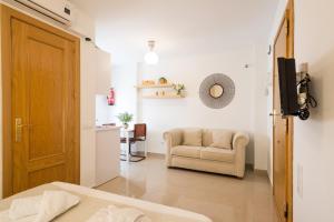 1 dormitorio con sofá y silla en una habitación en LU&CIA City Beach Puerto 1, en Málaga