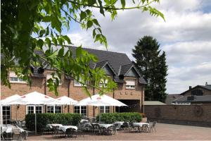 un bâtiment avec des tables et des parasols blancs devant lui dans l'établissement Haus Schönewald, à Dormagen