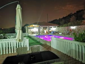 ein Pool in der Nacht mit einem Sonnenschirm und Stühlen in der Unterkunft Apartments Vila Lazarevic in Tivat