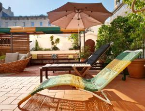 eine Terrasse mit 2 Stühlen, einem Tisch und einem Sonnenschirm in der Unterkunft The Central House Barcelona Gracia in Barcelona