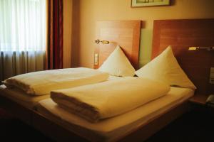 a bed with white sheets and pillows on it at Hotel & Restaurant Adler in Hornberg