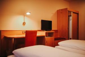 a hotel room with a desk with a television and a bed at Hotel & Restaurant Adler in Hornberg