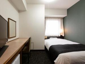 
a bedroom with a bed and a window at APA Hotel Sendai Kotodai Koen in Sendai
