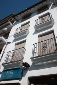 a white building with balconies and a sign on it at Hotel Don Pero in Alora