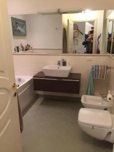 W łazience znajduje się umywalka, toaleta i lustro. w obiekcie PIANO TERRA CON GIARDINO VICINO AL MARE w Viareggio