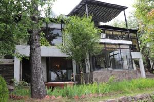 a house with black windows and a tree at Bhurban Valley Cottages 3 in Bhurban