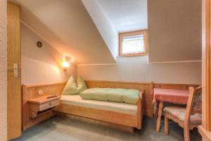 マトライ・イン・オストティロルにあるCafé Landerlのベッド、テーブル、窓が備わる小さな客室です。